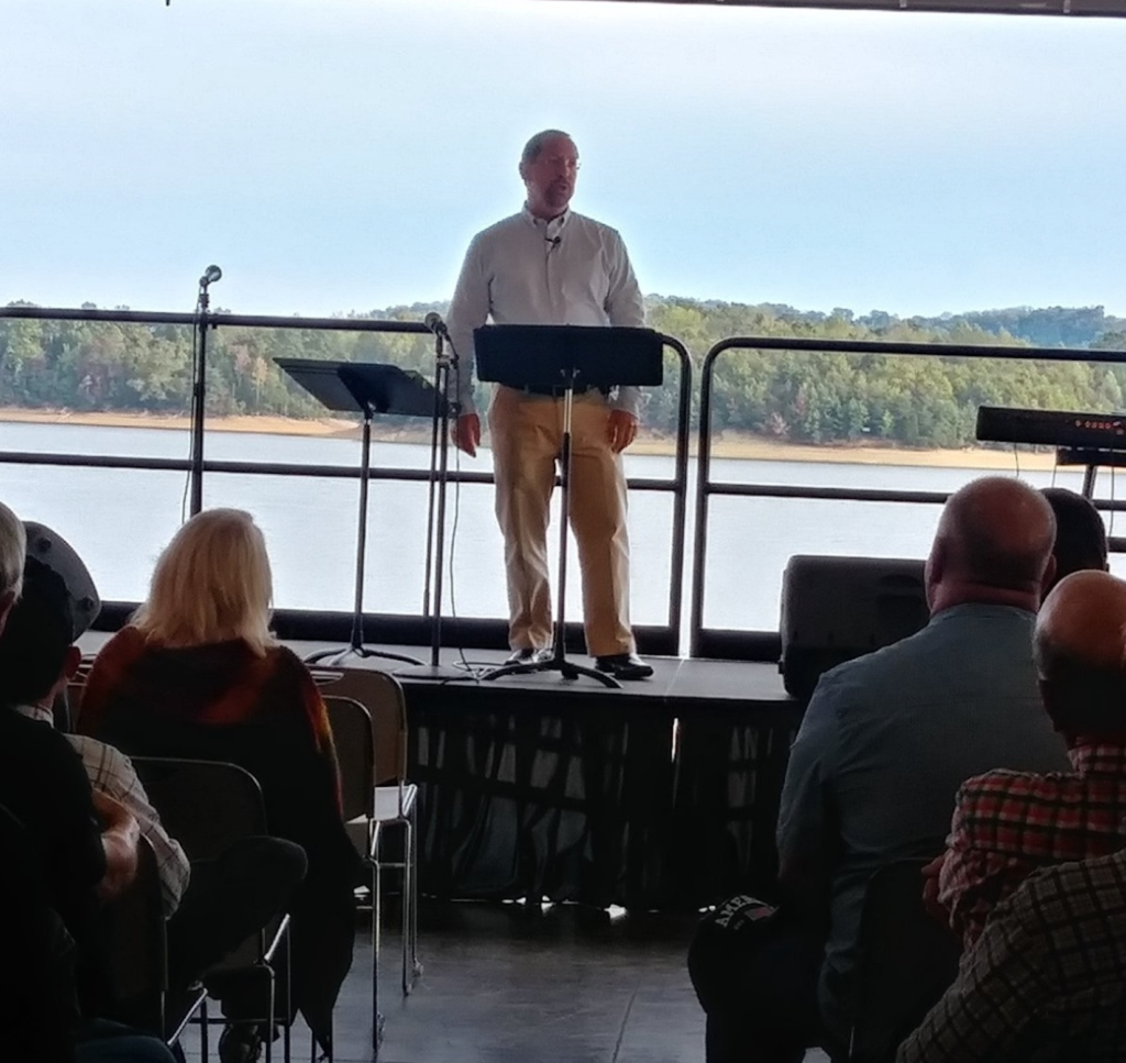 Man speaking on stage with audience.