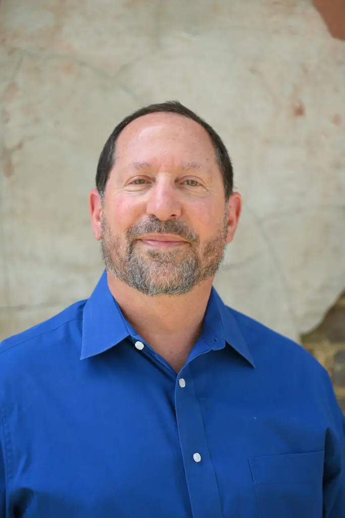 Man in blue shirt smiling at camera.
