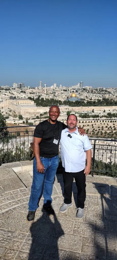 Two men stand with Jerusalem in background.