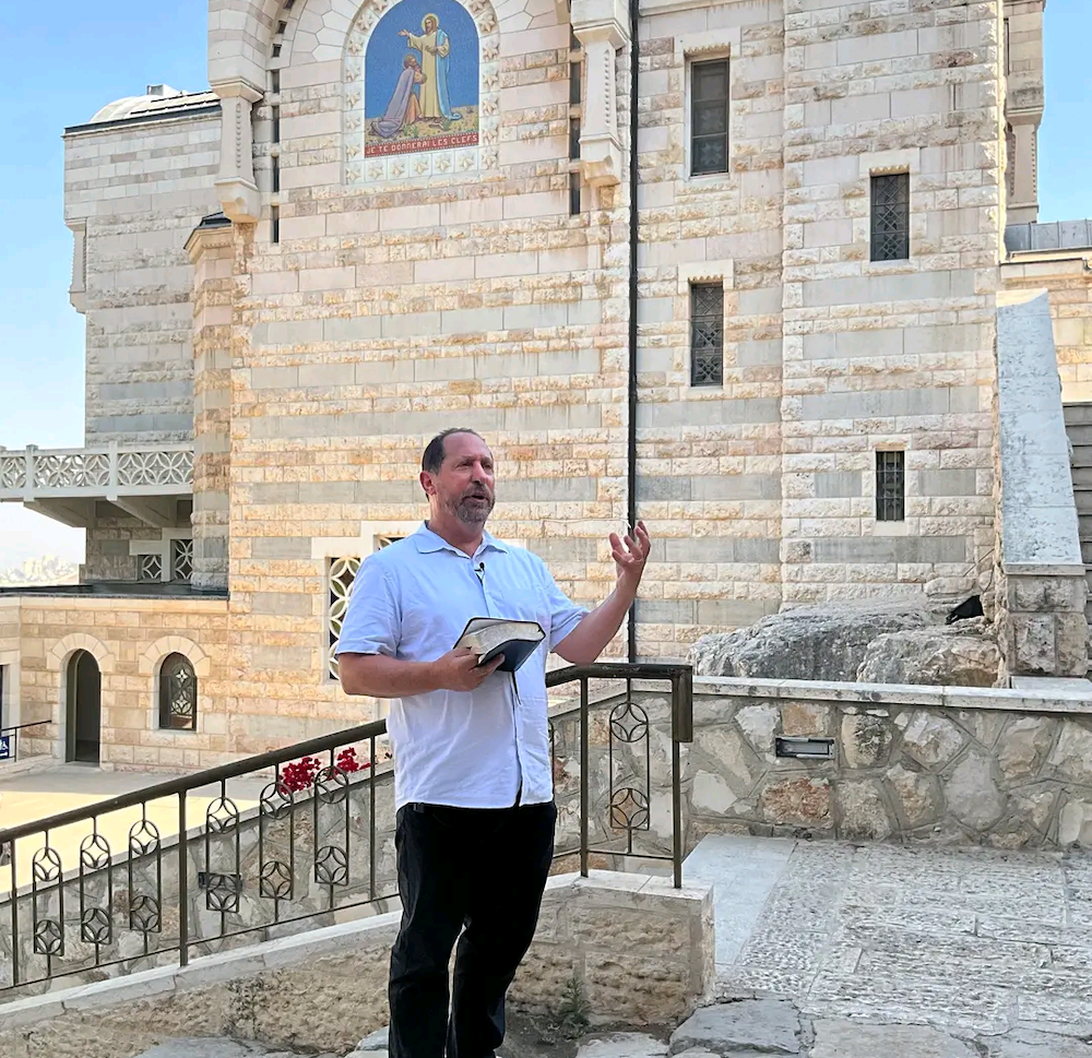 Man speaking outside a stone church.