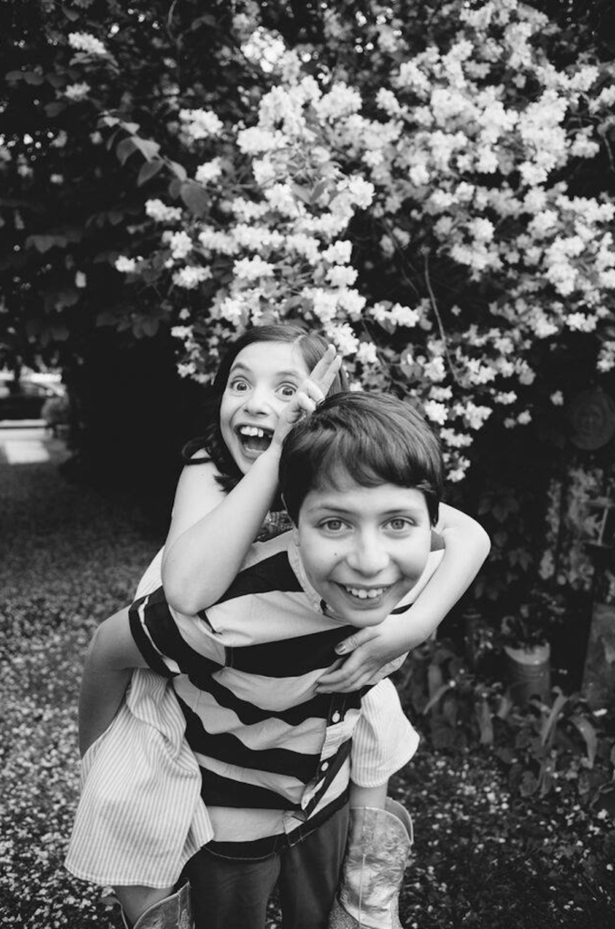 Girl piggybacks boy in black and white.