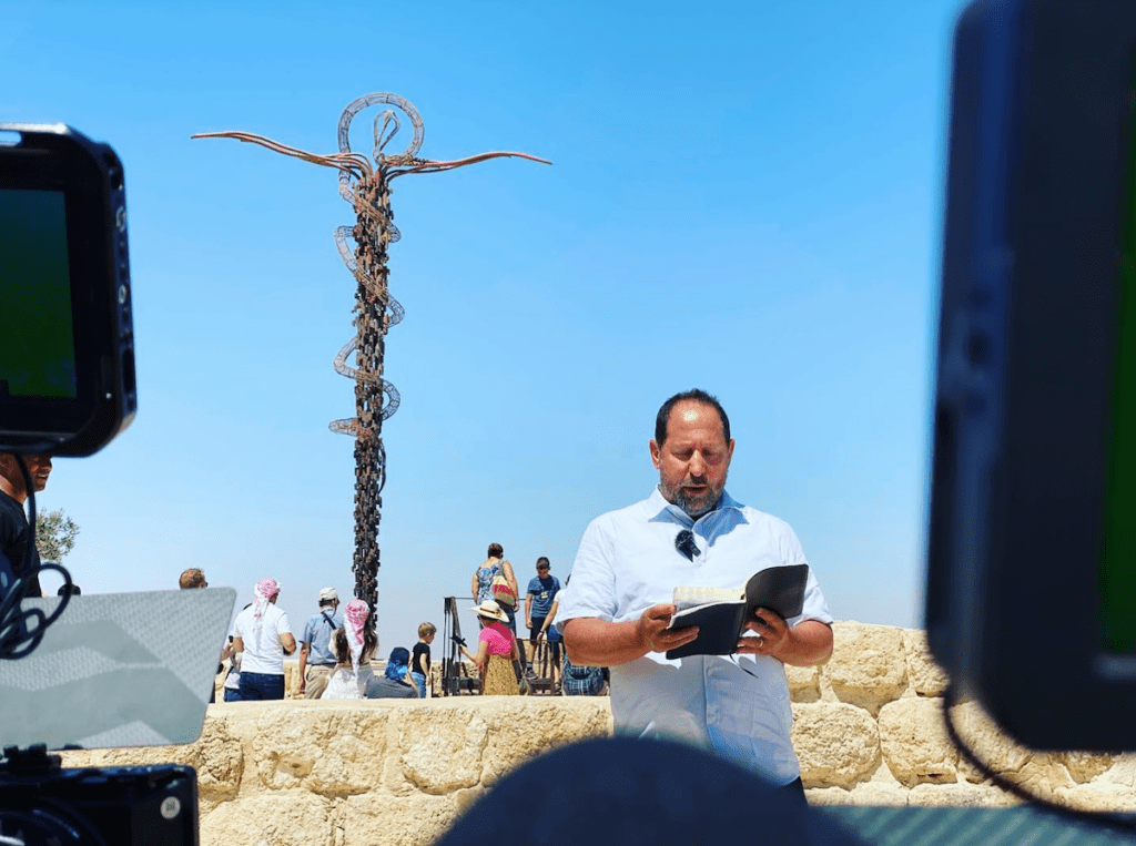 Man reading a book in front of sculpture.