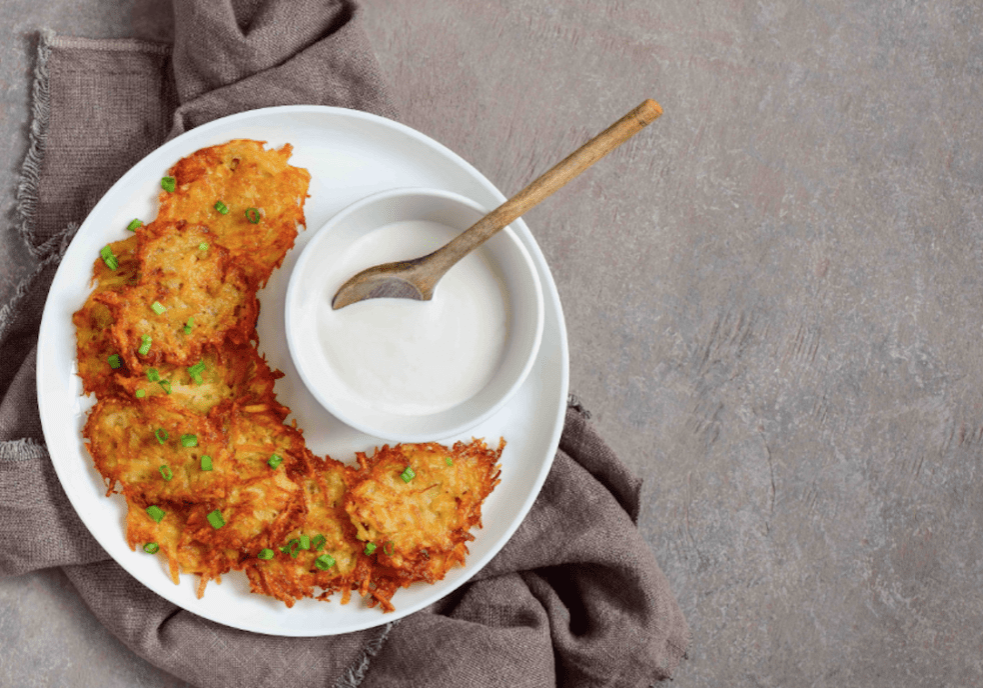 Potato pancakes with dipping sauce on a plate.