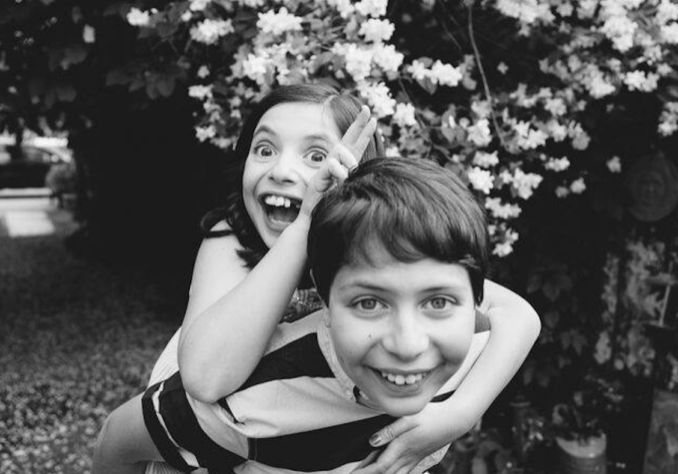 Black and white, two children smiling at the camera