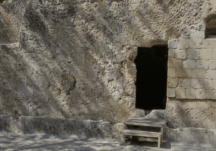 A stone wall with a door leading into a cave.